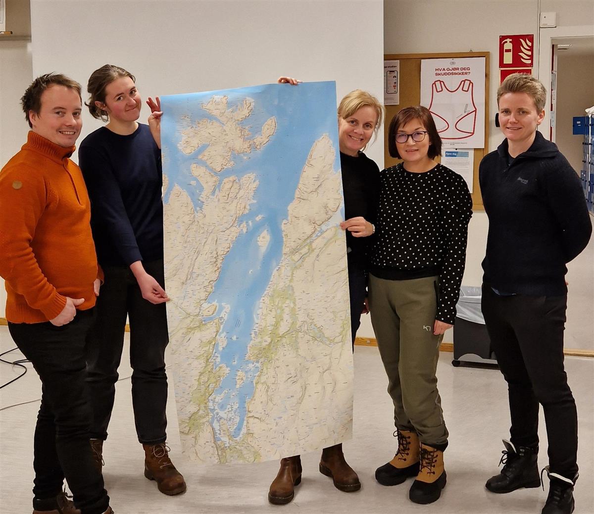 Alf Emil Paulsen, Solveig Bjørdal, Camilla Risvoll,Camilla Bratland og Ane Marthe Johannessen står med kart står ved et kart av Porsangerfjorden. (Foto) - Klikk for stort bilde